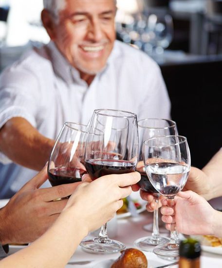 Mehrere Generationen essen gemeinsam und stoßen mit ihren Gläsern an